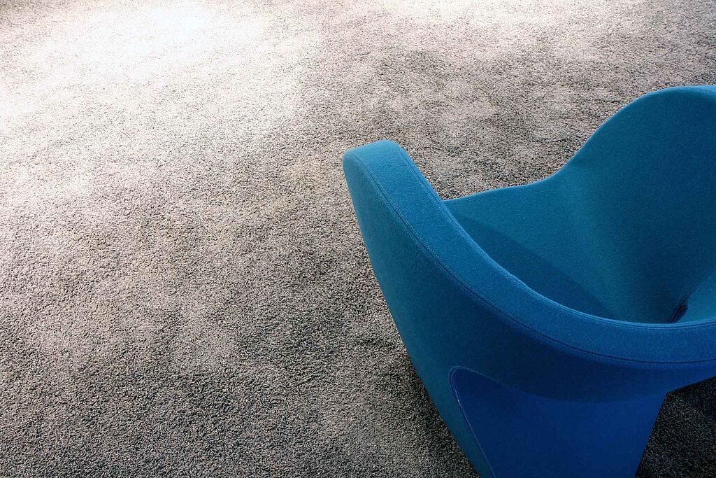 Grauer Teppichboden und blauer Lounge-Sessel
